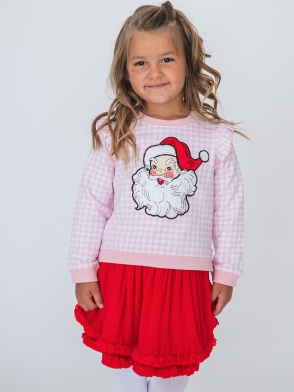 rufflebutts red tulle skirt Girl wearing Santa sweater and red skirt smiling.