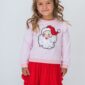 Girl wearing Santa sweater and red skirt smiling.