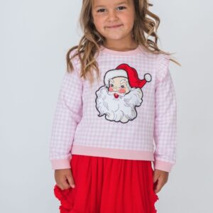 Child wearing Santa-themed outfit with red skirt.