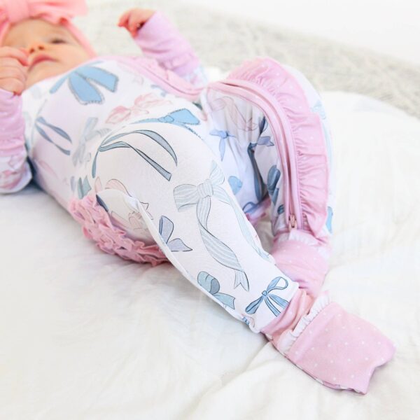 gigi and max samantha bows ruffle zip bamboo sleeplies little outfit Baby in bow-patterned pajamas with pastel colors.