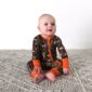 Baby wearing camo onesie on carpet.