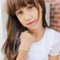 Young girl in white with pearl jewelry.
