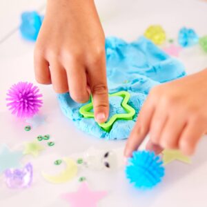 Child shaping blue dough with star cutter