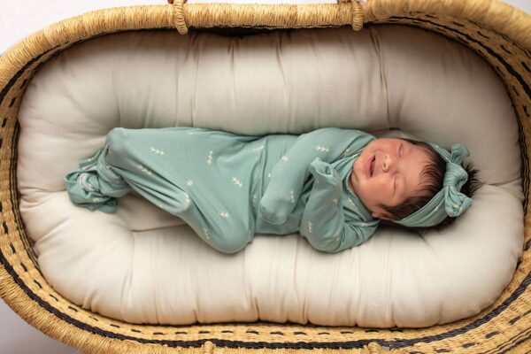three little tots arrow print knotted newborn baby gown pajamas Newborn sleeping in basket, wearing green outfit.