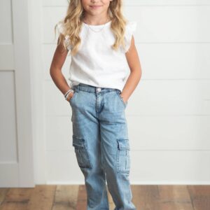 Child in white top and blue jeans smiling