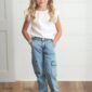 Child in white top and blue jeans smiling