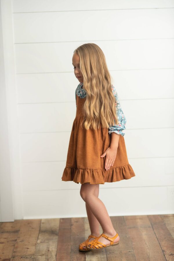 wren & james kids blue floral smocked top & caramel corduroy jumper set Girl with long hair wearing brown dress indoors.