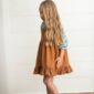Girl with long hair wearing brown dress indoors.