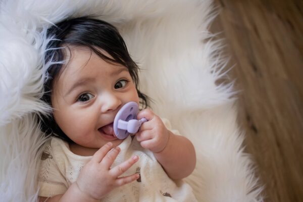 itzy ritzy sweetie soother™ pacifier sets (2 pack): agave + succulent cables Baby with pacifier on white blanket
