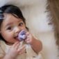 Baby with pacifier on white blanket
