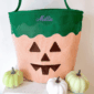 Striped jack-o'-lantern bucket with small white pumpkins.