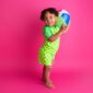 Child holding beach ball on pink background.