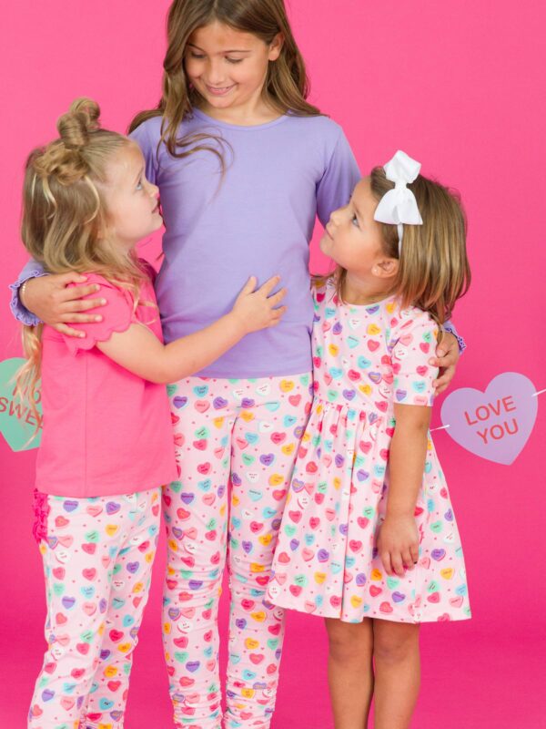 rufflebutts + ruggedbutts girls be my valentine short sleeve knit twirl dress Three girls in colorful heart pajamas smiling