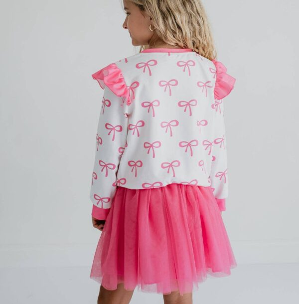 product Girl wearing pink ruffle dress with bows.