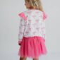 Girl wearing pink ruffle dress with bows.