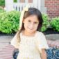 Smiling child with yellow ribbon outdoors.