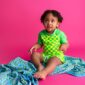 Toddler in green checkered outfit on pink background.