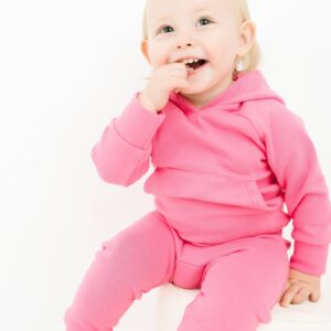 Smiling toddler in pink outfit sitting happily.