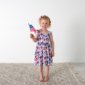 Child holding American flag in floral dress