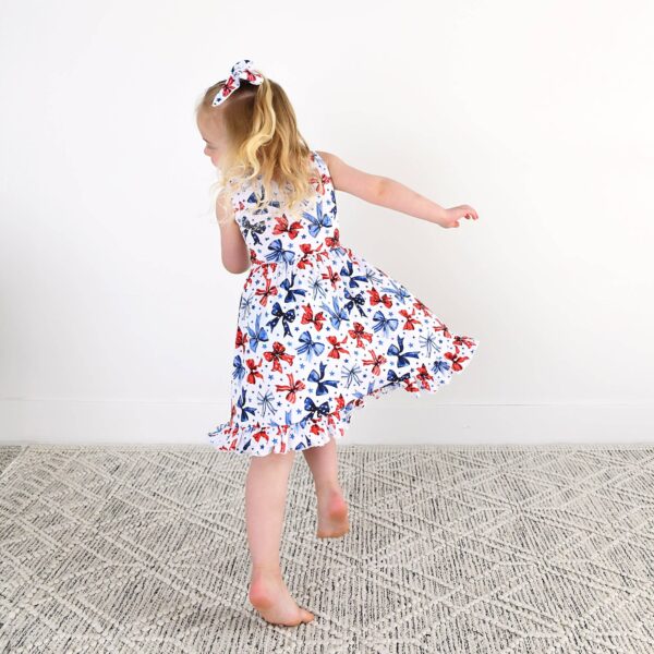 gigi and max eleanor bow clip bow 4th of july hair accessory Child in floral dress twirls joyfully on carpet.