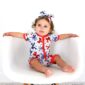 Baby in patriotic romper on chair.