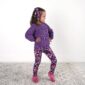 Child wearing purple sweater and floral leggings.
