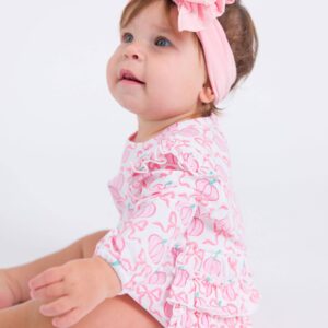 Baby in pink outfit with headband.