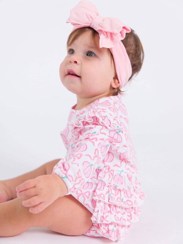 rufflebutts + ruggedbutts baby girls pink fairytale pumpkins knit long sleeve flutter bubble romper Baby in pink outfit with headband.
