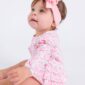 Baby in pink outfit with headband.