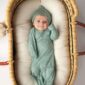 Baby in green outfit lying in basket