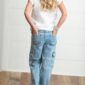 Child in white shirt and jeans, hands in pockets.