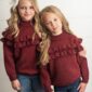 Two girls in matching burgundy sweaters and jeans.