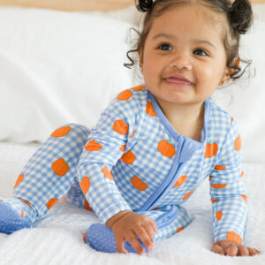 Baby in pumpkin pajamas crawling on bed