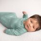 Newborn baby in green outfit on blanket