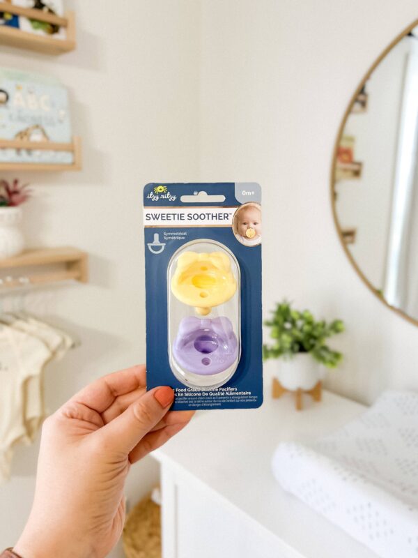 itzy ritzy sweetie soother™ pacifier sets (2 pack): agave + succulent cables Hand holding Sweetie Soother pacifiers in nursery.
