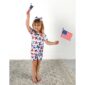 Child waving American flags joyfully in printed outfit.