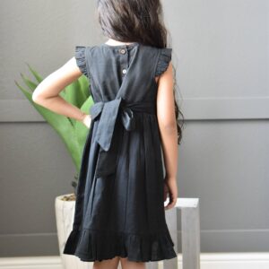 Child in black dress with bow, back view.