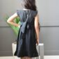 Child in black dress with bow, back view.