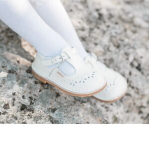 Child's white shoes on rocky surface.