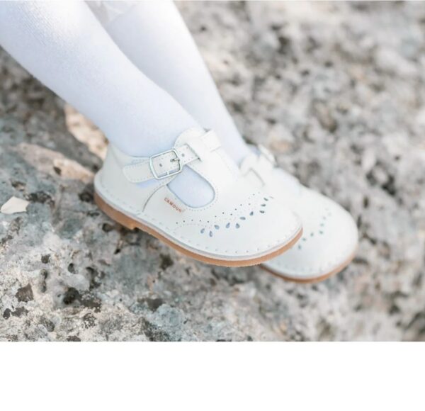 Child's white shoes on rocky surface.