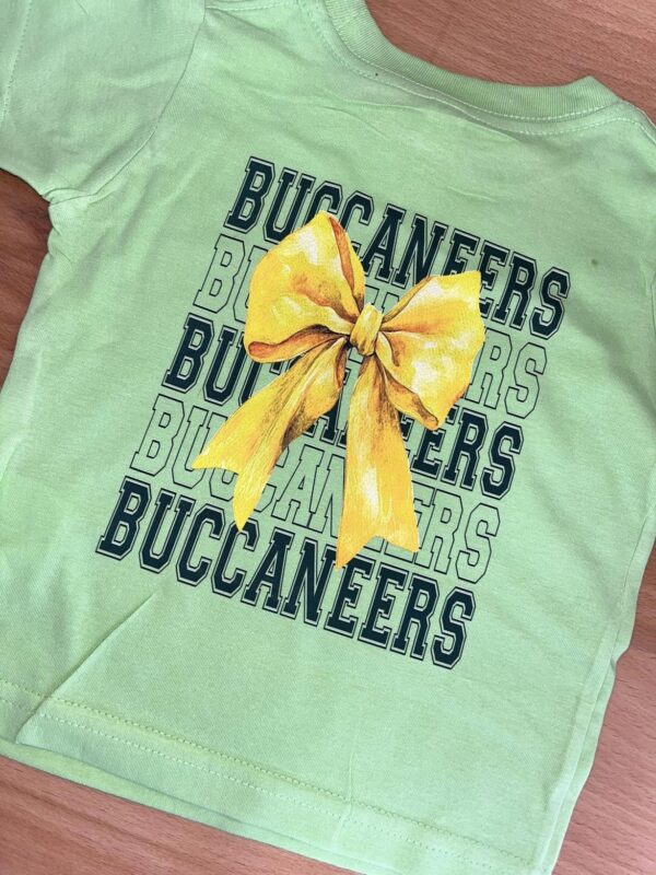 Green shirt, yellow bow, Buccaneers text design.
