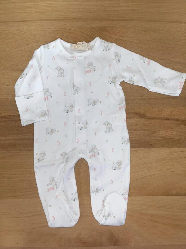 White baby onesie with lamb pattern on wooden surface.