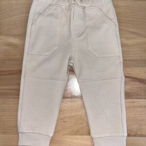 Beige toddler pants on wooden floor.