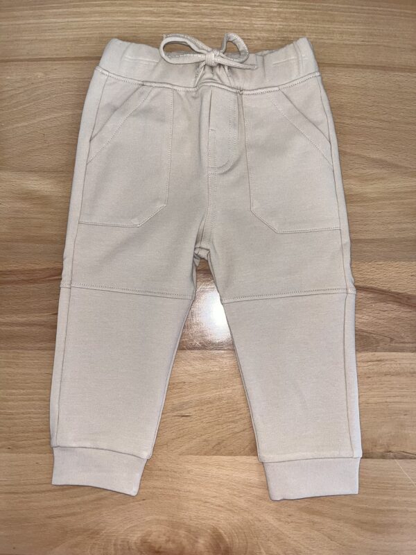 Beige toddler pants on wooden floor.