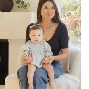 Woman with baby sitting indoors on chair.