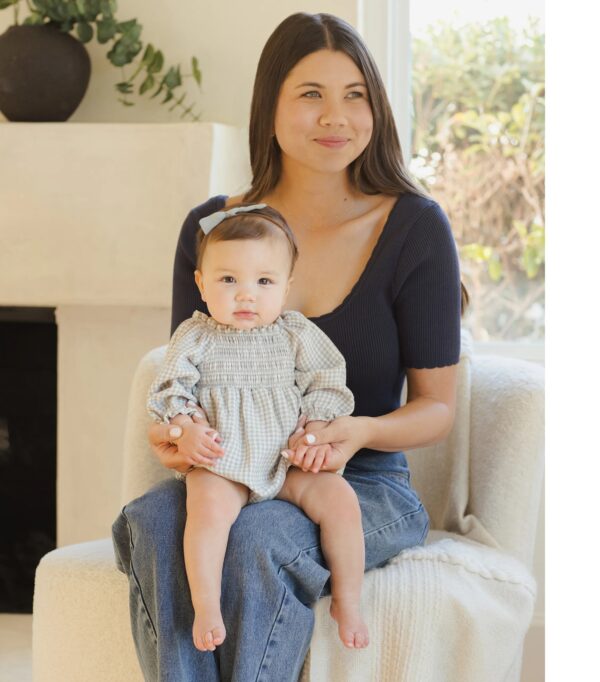 quincy mae eden romper blue gingham Woman with baby sitting indoors on chair.