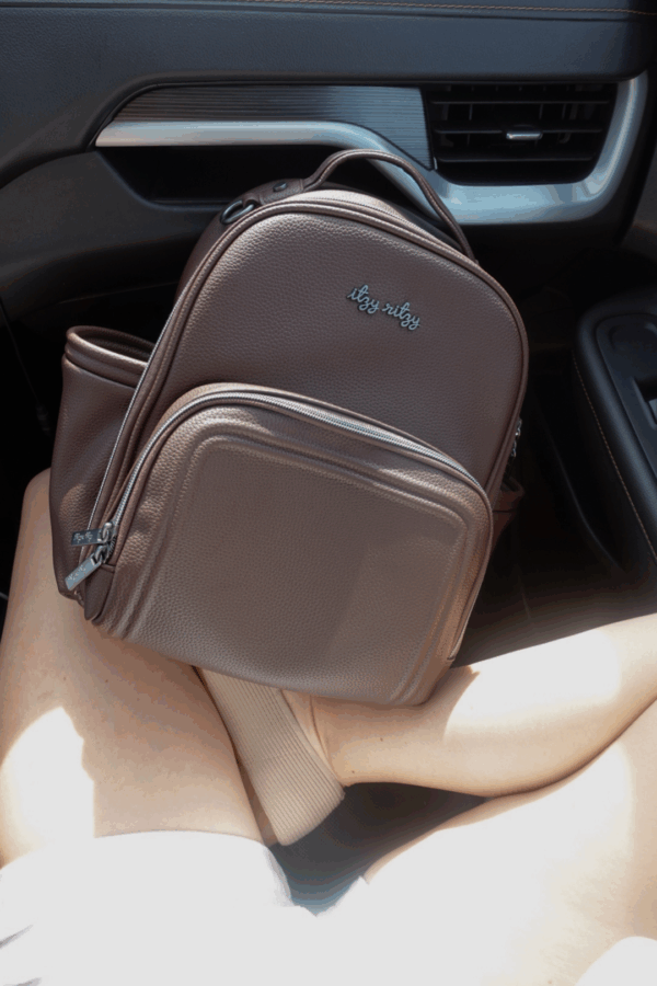 itzy ritzy *new* espresso itzy mini plus™ Brown backpack on person's lap in car