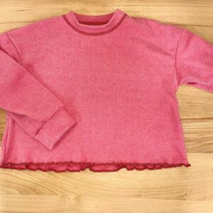 Red long-sleeve shirt on wooden surface.