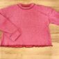 Red long-sleeve shirt on wooden surface.