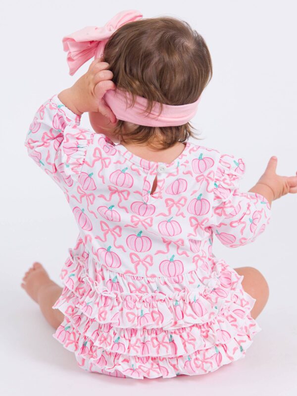 rufflebutts + ruggedbutts baby girls pink fairytale pumpkins knit long sleeve flutter bubble romper Baby in pink pumpkin-patterned dress, pink headband